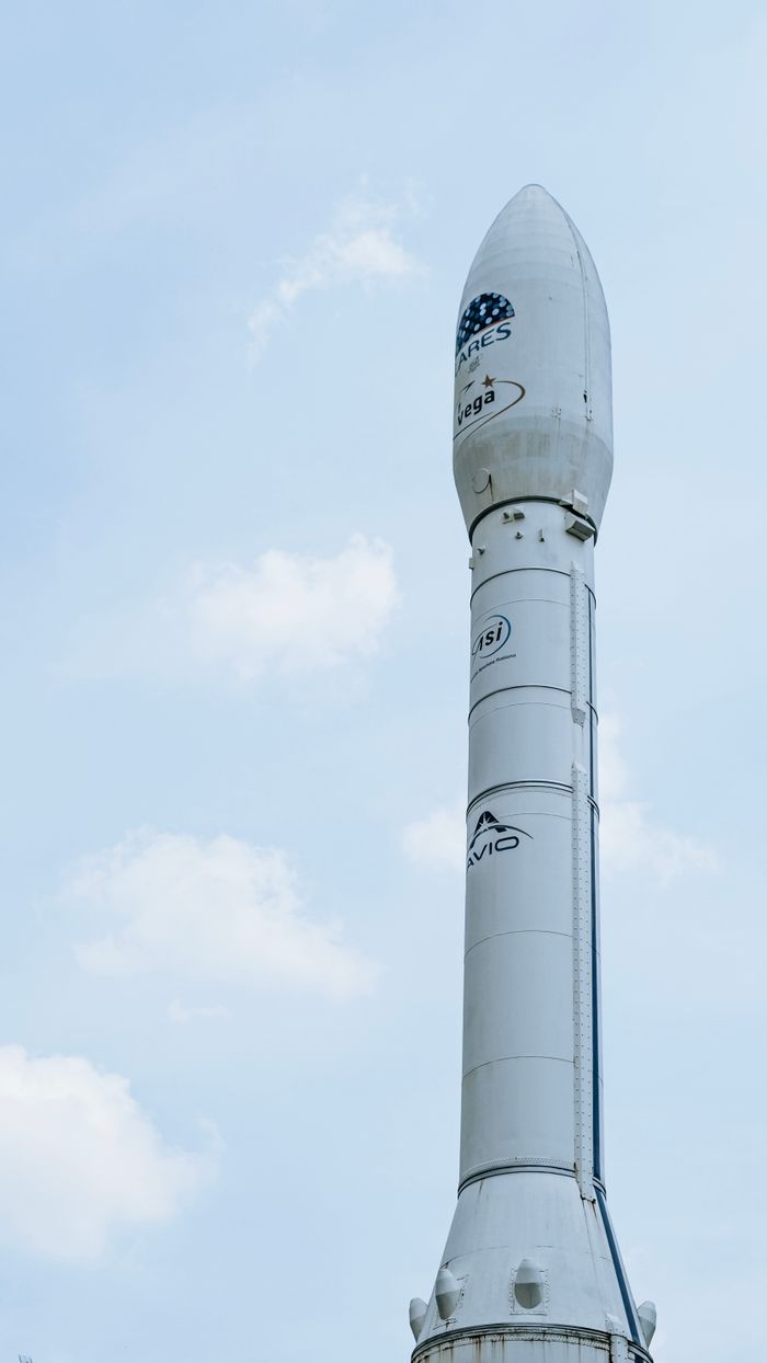 A close-up view of a tall white rocket set against a partly cloudy blue sky.